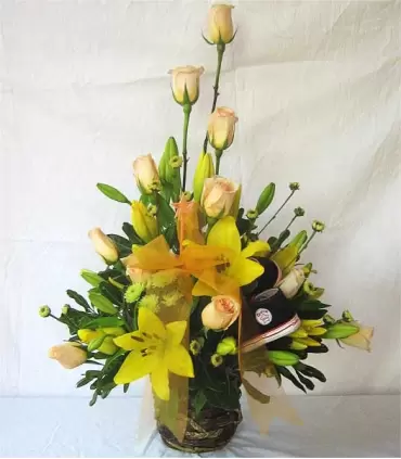 Canasta con rosas, liliums y zapatitos para niño recién nacido.