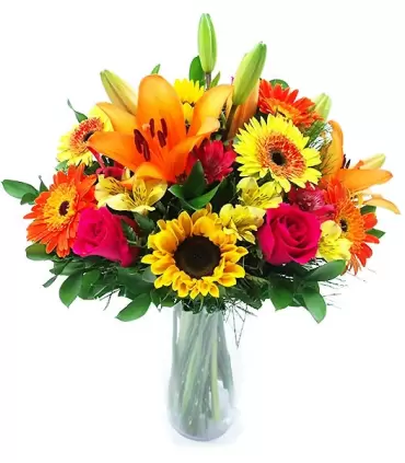 Florero con flores surtidas: girasoles, liliums, rosas y gerberas.