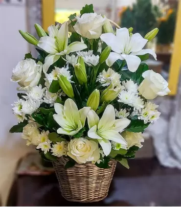Canastillo de flores blancas con 5 rosas blancas, 5 liliums blancos y maules.